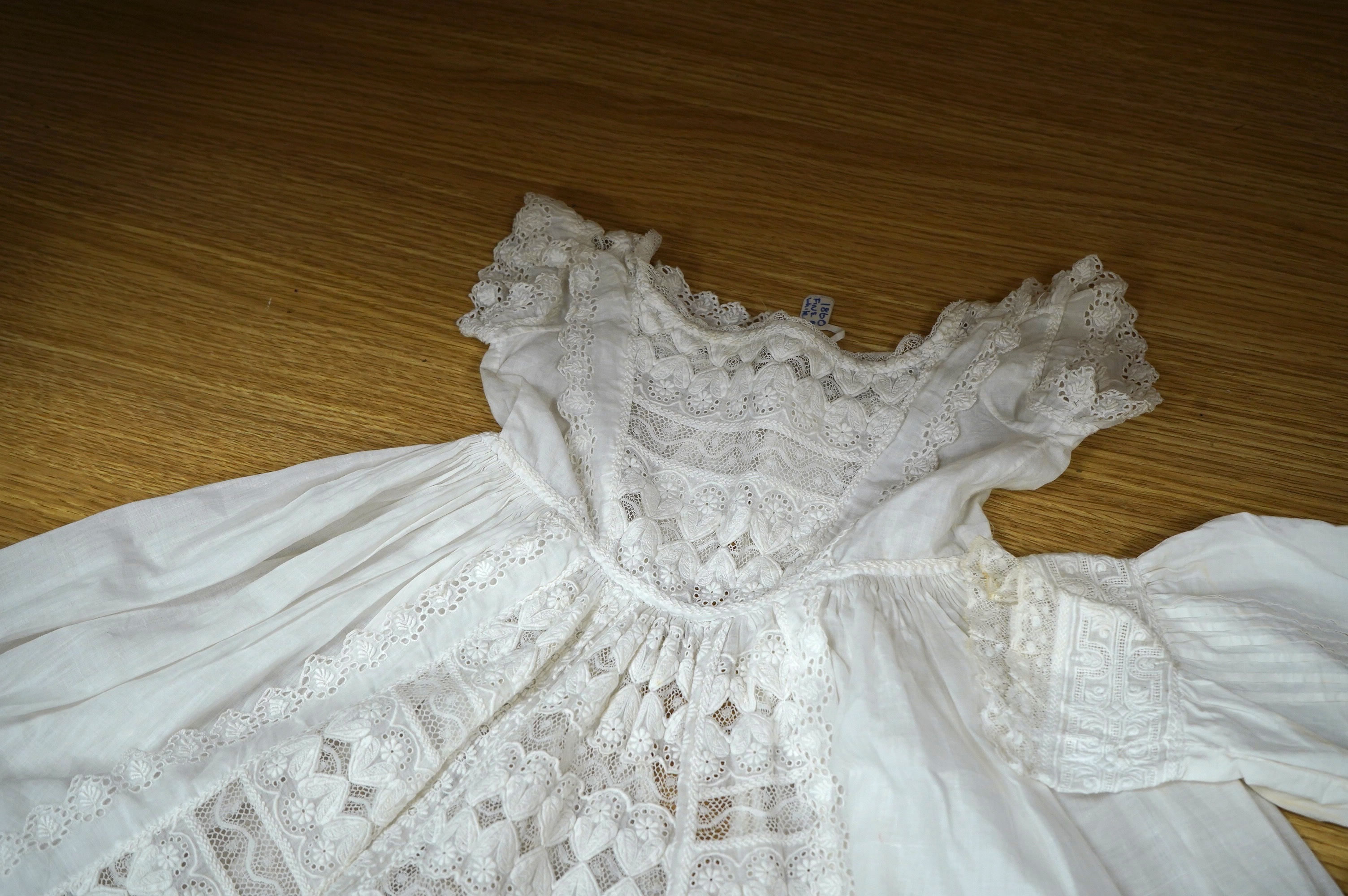 Two unusual 19th century intricately white worked children’s dresses, one hand worked with fine panels of white work, feather stitching and tucking, edged and inserted with hand made Valenciennes lace, the other worked i